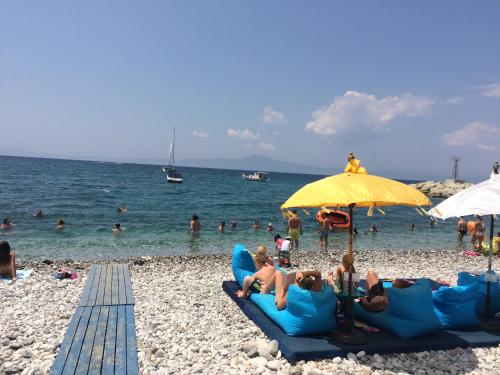 a group of people sitting on the beach under an umbrella at Agali 1 Mesonet In Front Of The Sea in Akrogiali