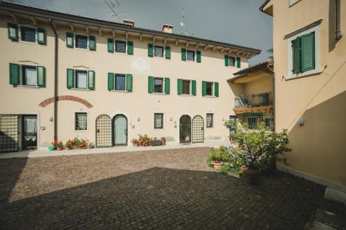 a large white building with green windows and a courtyard at A Casa di Tom in SantʼAmbrogio di Valpolicella