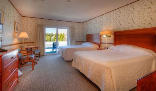een hotelkamer met 2 bedden en een raam bij The Seaside Inn in Kennebunk Beach