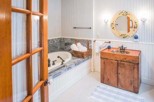 een badkamer met een bad, een wastafel en een spiegel bij Round Barn Farm B & B Event Center in Red Wing