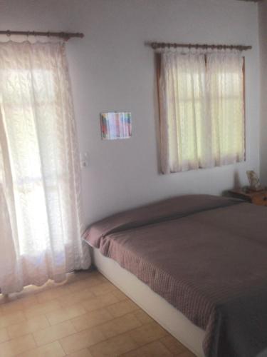a bedroom with a bed and two windows at Villa Nelly by the sea in Néa Koróni