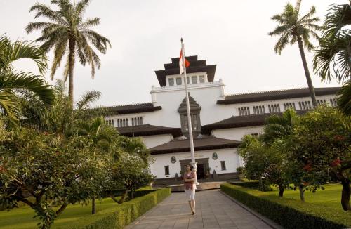 a woman walks in front of a building at Hotel Santika Bandung in Bandung