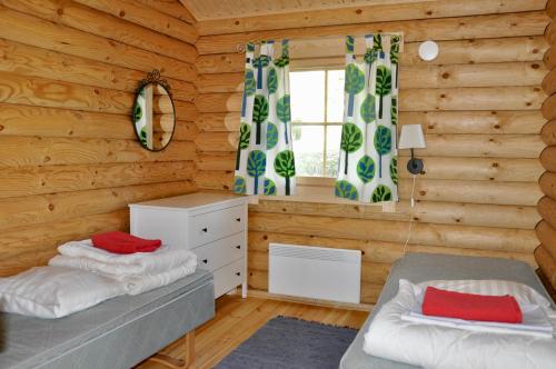 a bedroom with two beds in a log cabin at Hotel Hanhi Cottages in Lapinjärvi