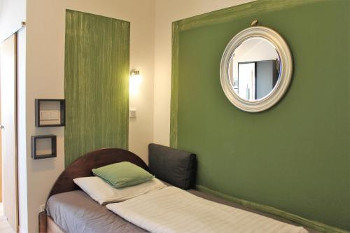 a bedroom with a green wall and a mirror at Appartementhaus Witzmann in Bad Vöslau
