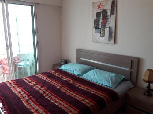 een slaapkamer met een bed met een deken en een raam bij Océan in Rabat