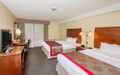 Habitación de hotel con 2 camas y escritorio en Ramada by Wyndham Niagara Falls by the River en Niagara Falls