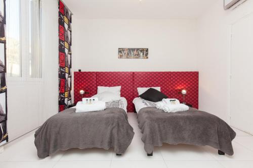 - une chambre avec 2 lits et une tête de lit rouge dans l'établissement Manhattan 2 pièces 3 étoiles lumineux plein centre à 5mn des plages et palais, à Cannes