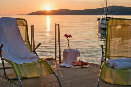 twee stoelen en een vaas met een bloem op het strand bij Apartmani Gacina in Grebaštica