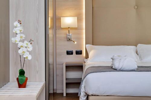 1 dormitorio con 1 cama y un jarrón con flores blancas en Duomo Hotel & Apartments en Milán