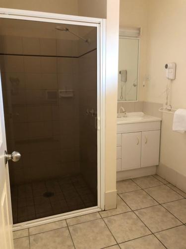 a bathroom with a shower with a glass door at Outback Quarters Motel Hay and Restaurant in Hay