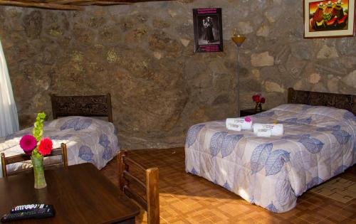a hotel room with two beds and a table and a table sidx sidx at La Granja del Colca in Cabanaconde