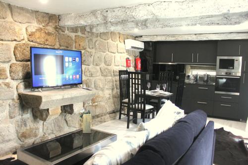 a living room with a couch and a tv on a stone wall at Casa do Largo do Cais in Vila Nova de Cerveira