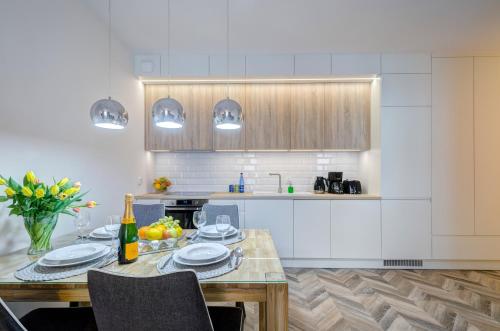 a kitchen with a table with plates and a bottle of wine at Live & Travel Apartments Number 1 in Gdańsk