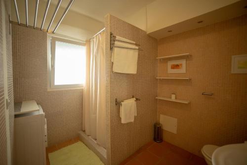 a bathroom with a toilet and a window and towels at Apartamento Troino in Setúbal