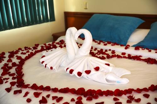 two white swans on a bed covered in roses at Hotel Donde Marcelo in Baños