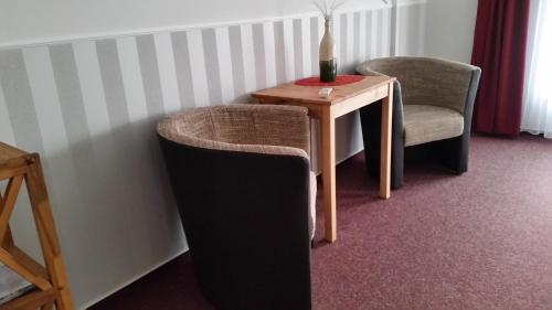 a room with a table and a chair and a bottle of wine at Pension Am Dorfanger in Hohennauen