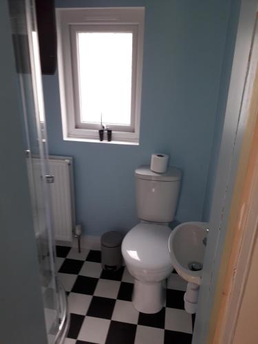 a bathroom with a toilet and a window and a checkered floor at Seawinds in Kyle of Lochalsh