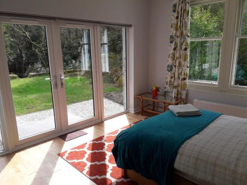 a bedroom with large windows and a bed with blue sheets at Seawinds in Kyle of Lochalsh