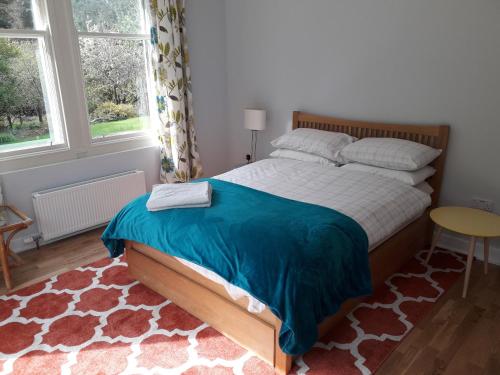 a bedroom with a bed and a table and two windows at Seawinds in Kyle of Lochalsh