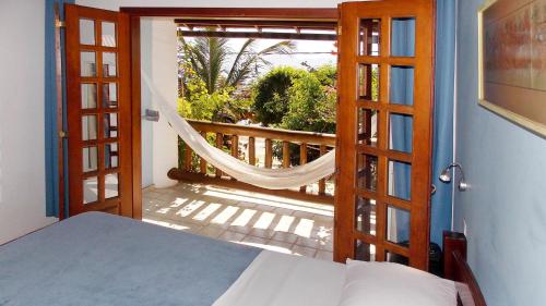 a bedroom with a door open to a balcony with a hammock at Pousada Manaca in Abraão