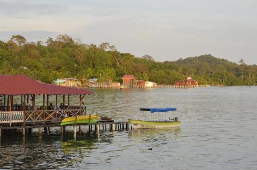 a dock with a restaurant and a boat on a lake at Beverly's Hill Guest House in Bocas del Toro