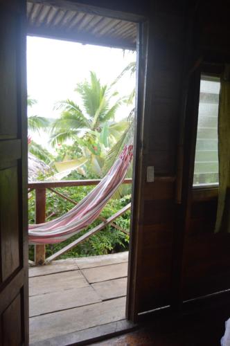 a hammock on a porch with a palm tree at Beverly's Hill Guest House in Bocas del Toro