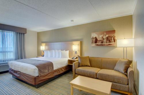 a hotel room with a bed and a couch at Best Western Royal Plaza Hotel and Trade Center in Marlborough