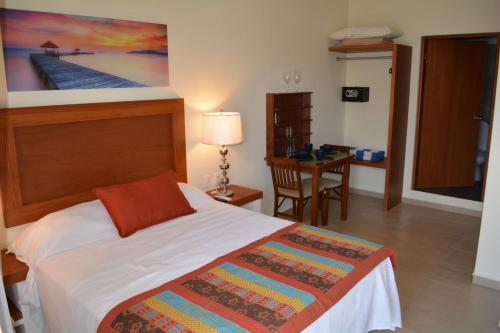 a bedroom with a bed and a table with a desk at Suites SanRey in Puerto Morelos