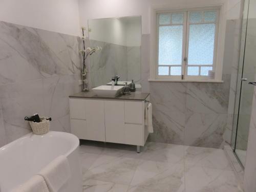 un bagno bianco con vasca, lavandino e vasca di Keillor Lodge a Maleny