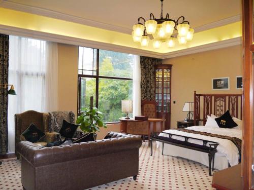 a bedroom with a bed and a couch and a chair at The White House Museum Hotel Guilin in Guilin