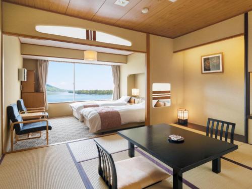 宮津市にある天橋立ホテルのベッドとテーブル付きのホテルルームとベッドルーム1室が備わります。