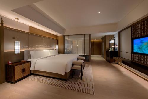 a bedroom with a bed and a flat screen tv at Pan Pacific Yangon in Yangon