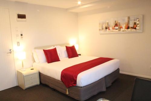 a hotel room with a large bed with red pillows at Bealey Plaza Motel in Christchurch