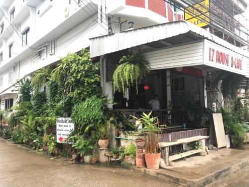 un edificio con plantas y un banco delante de él en EZ House en Sukhothai