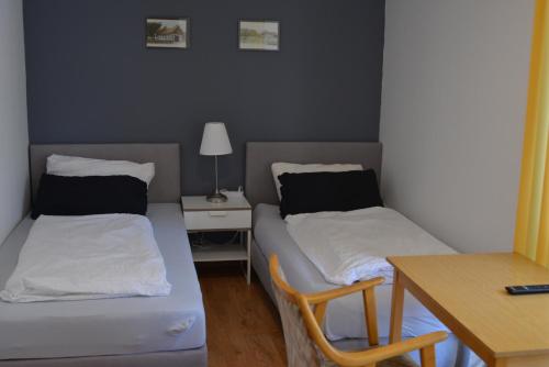 a room with two beds and a table with a lamp at Hotel Hages in Bad Salzuflen