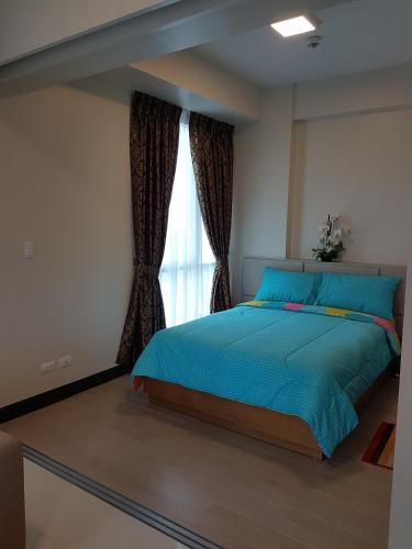 a bedroom with a blue bed and a window at Apartment Sea View at Mactan Newtown in Mactan