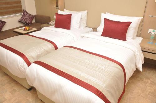 two beds in a hotel room with red pillows at Days Hotel Jaipur Tonk Road By Wyndham in Jaipur