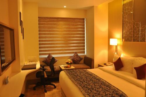 a hotel room with a bed and a desk and a window at Days Hotel Jaipur Tonk Road By Wyndham in Jaipur