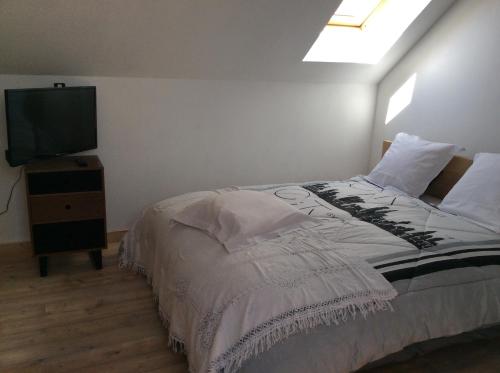 a bedroom with a bed and a flat screen tv at Gîtes du Grand Bois in Maubeuge