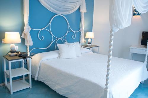 a bedroom with a white bed and a blue wall at Hotel Cutimare - Aeolian Charme in Acquacalda