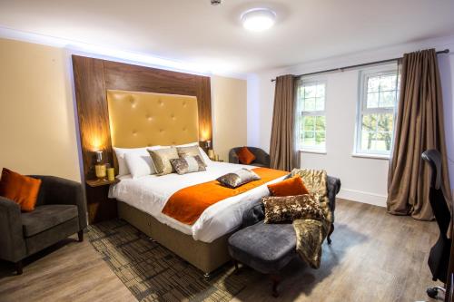 a bedroom with a large bed and a chair and window at Trivelles Gatwick Hotel & airport Parking in Crawley