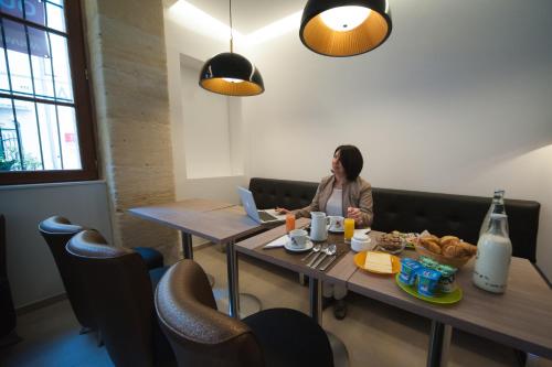 a woman sitting at a table with a laptop at Central Hotel in Nîmes