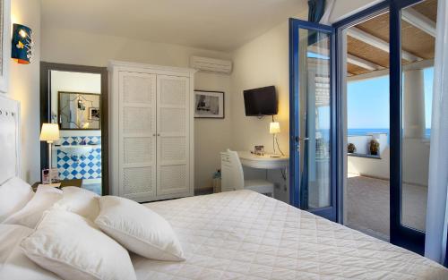 a bedroom with a bed and a desk with a computer at Hotel Cutimare - Aeolian Charme in Acquacalda