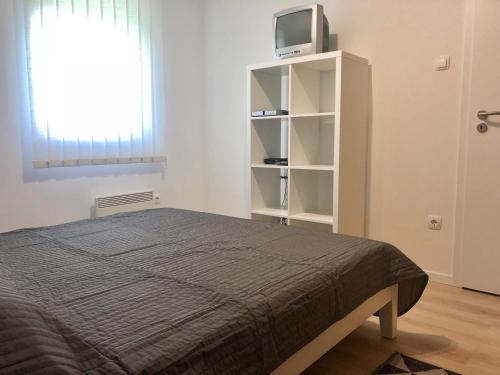 1 dormitorio con 1 cama y TV en un estante en Geri Apartman, en Mezőkövesd