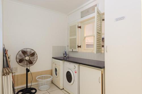 a laundry room with a washing machine and a fan at Skiathos 8 - FAMILY ONLY - Max 6 adults and 2 children in Ballito