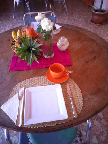 a wooden table with a white plate and a bowl of flowers at Villa Victoria in Trou dʼ Eau Douce