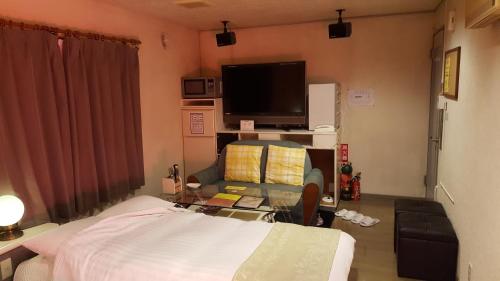a living room with a bed and a tv at Hotel Vegas (Adult Only) in Sapporo