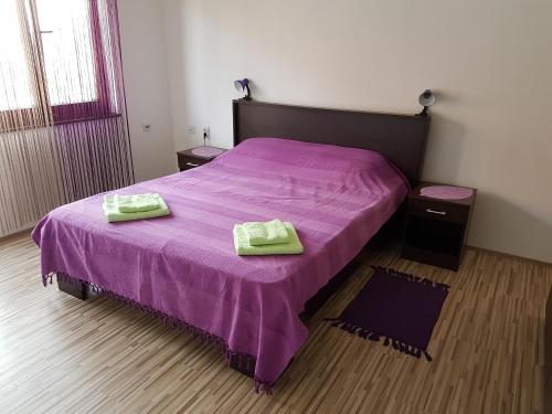1 dormitorio con 1 cama morada y 2 toallas en S&G Apartment en Vranje