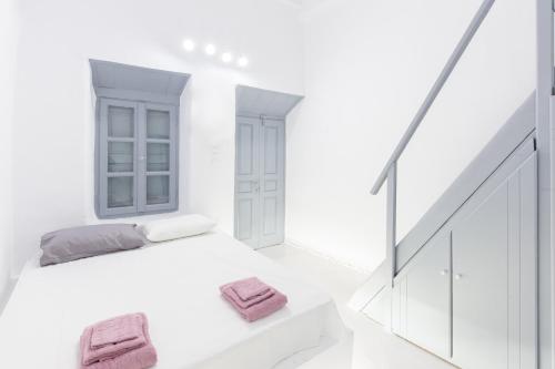 Melina's House Mykonos Town في مدينة ميكونوس: غرفة بيضاء مع سرير ومناشف وردية