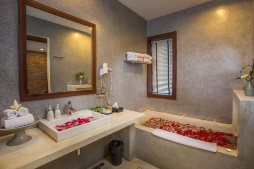 ein Bad mit 2 Waschbecken und einer Badewanne mit roten Blumen in der Unterkunft Nita by Vo Luxury Hotel in Siem Reap